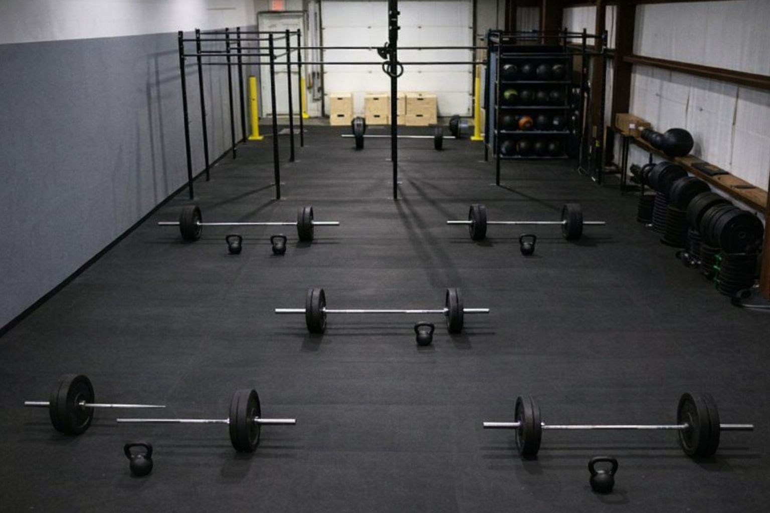 En rymlig gymlokal med skivstänger och kettlebells på gummimattor.