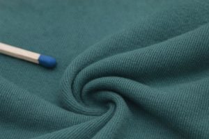 Närbild på grönt hoodie-tyg med en tändsticka som storleksreferens.