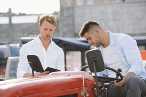 Två män inspekterar en röd traktor vid en försäljning eller auktion.