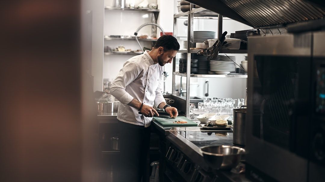 En professionell kock arbetar i ett modernt restaurangkök med rostfri utrustning.